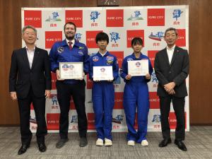 米国・宇宙ロケットセンター主催の宇宙教育プログラム「スペースキャンプ」に参加した両城中学校の 岡本恵麻 さん，裏山大智 さん，引率教員の ジョーンズ・ニコラス さんほか