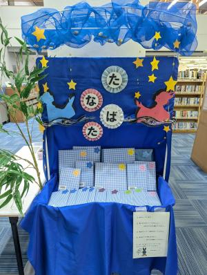 たなばた☆フェアの飾り付け展示。織姫と彦星をイメージした飾り付けや,ラッピングされた本がある。短冊を吊す笹も端の方に写っている。